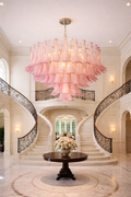 Large pink petal glass tiered chandelier suspended in a grand double-staircase foyer.