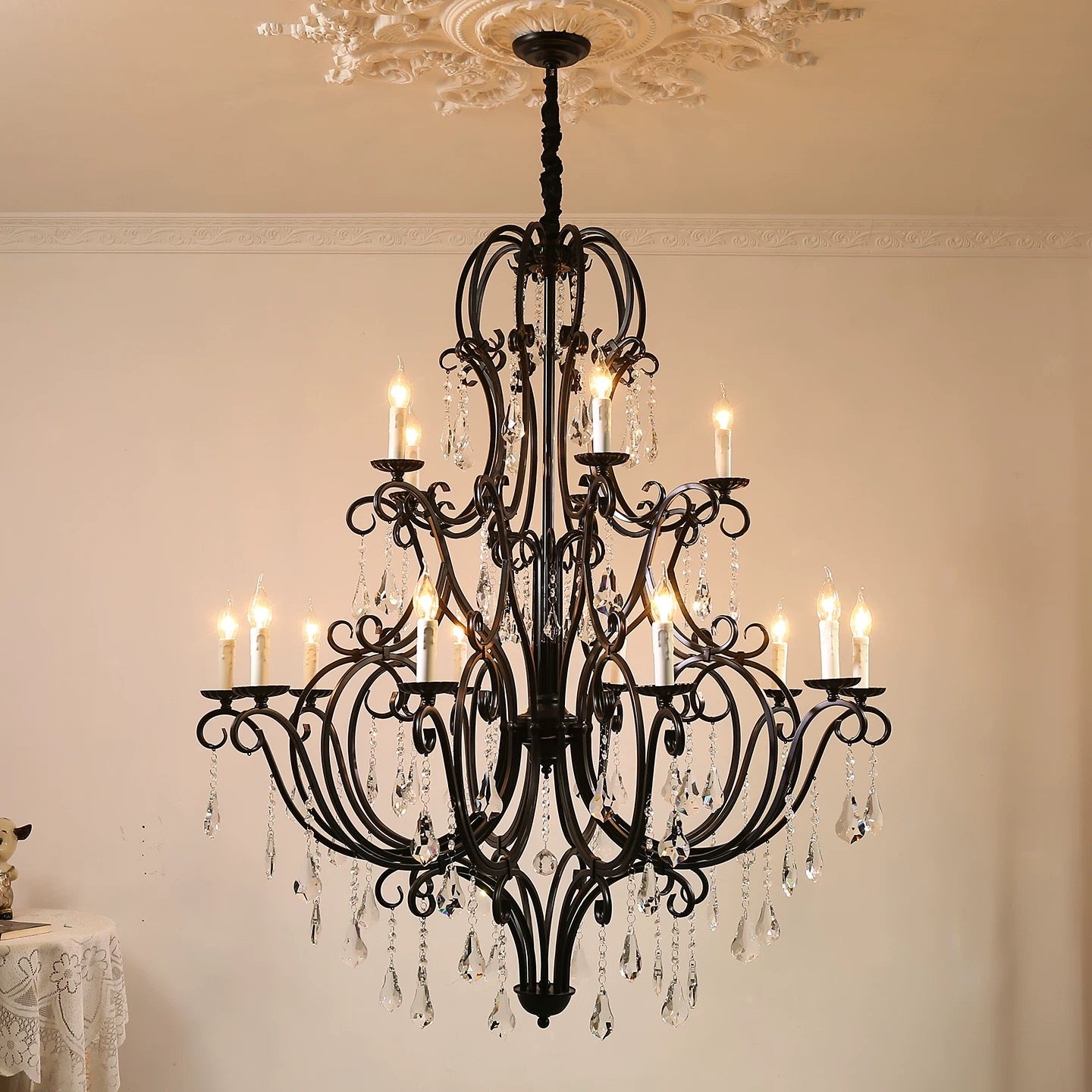 Black wrought-iron chandelier glowing beneath a decorative ceiling medallion.
