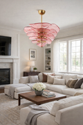 Blush-pink sculptural glass chandelier with layered organic forms in a bright living room.