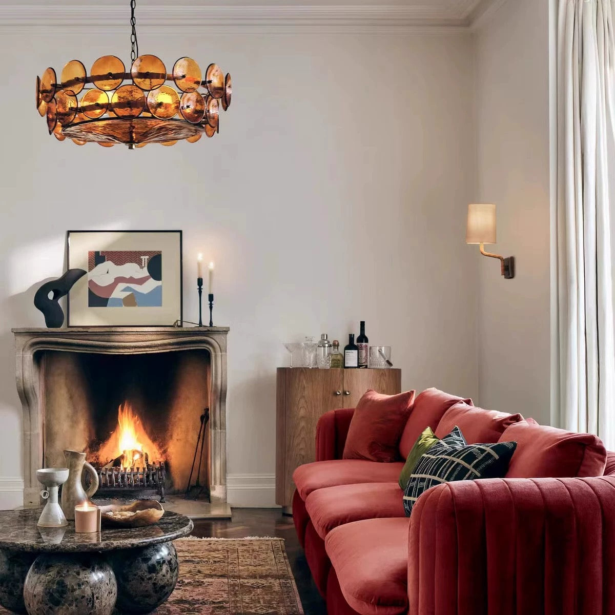 Amber disc glass drum chandelier above a fireplace in a warm contemporary living room.