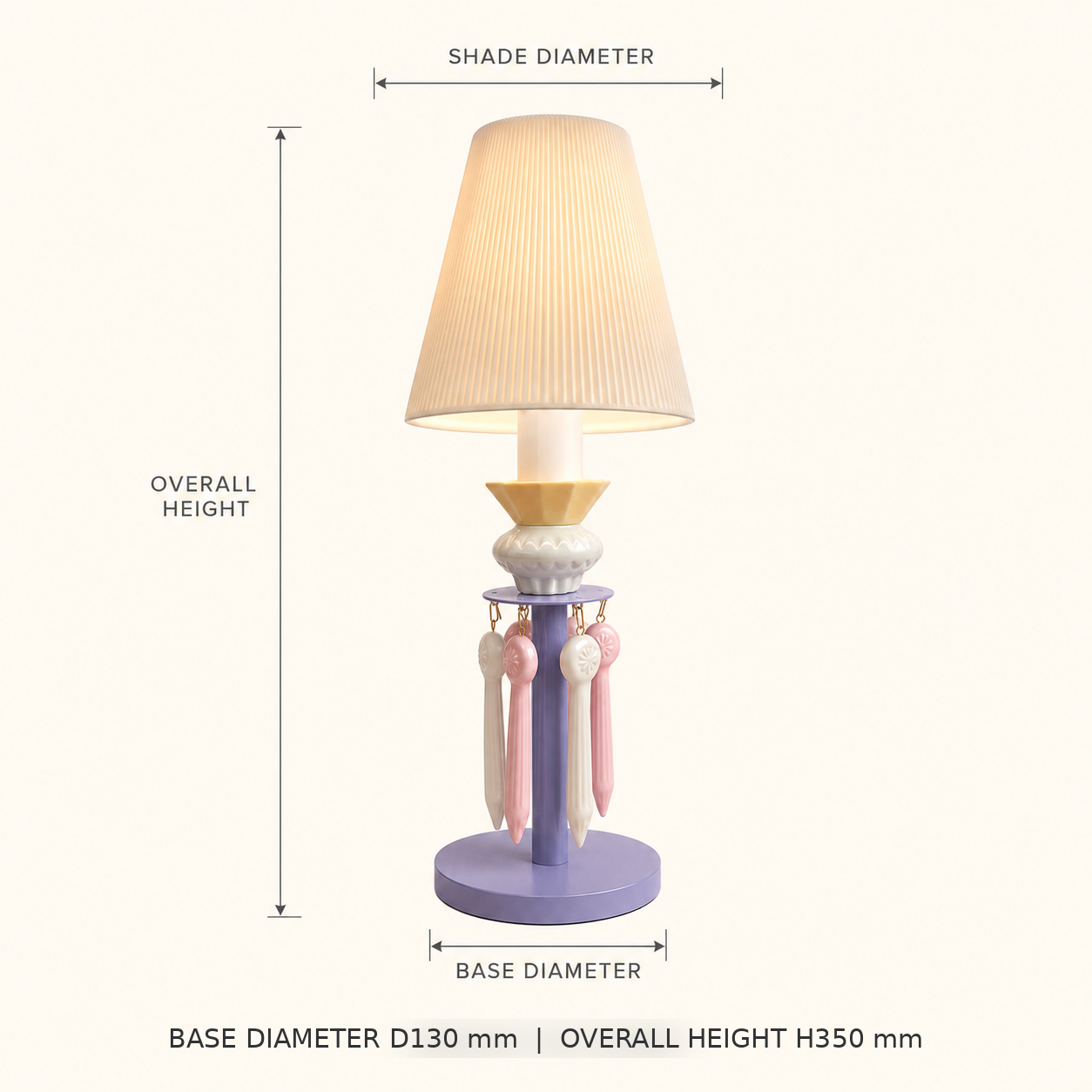 A table lamp with a pleated beige shade, lavender base, and pastel pink and cream hanging tassels, shown with dimension labels for shade diameter, overall height, and base diameter on a light beige background.