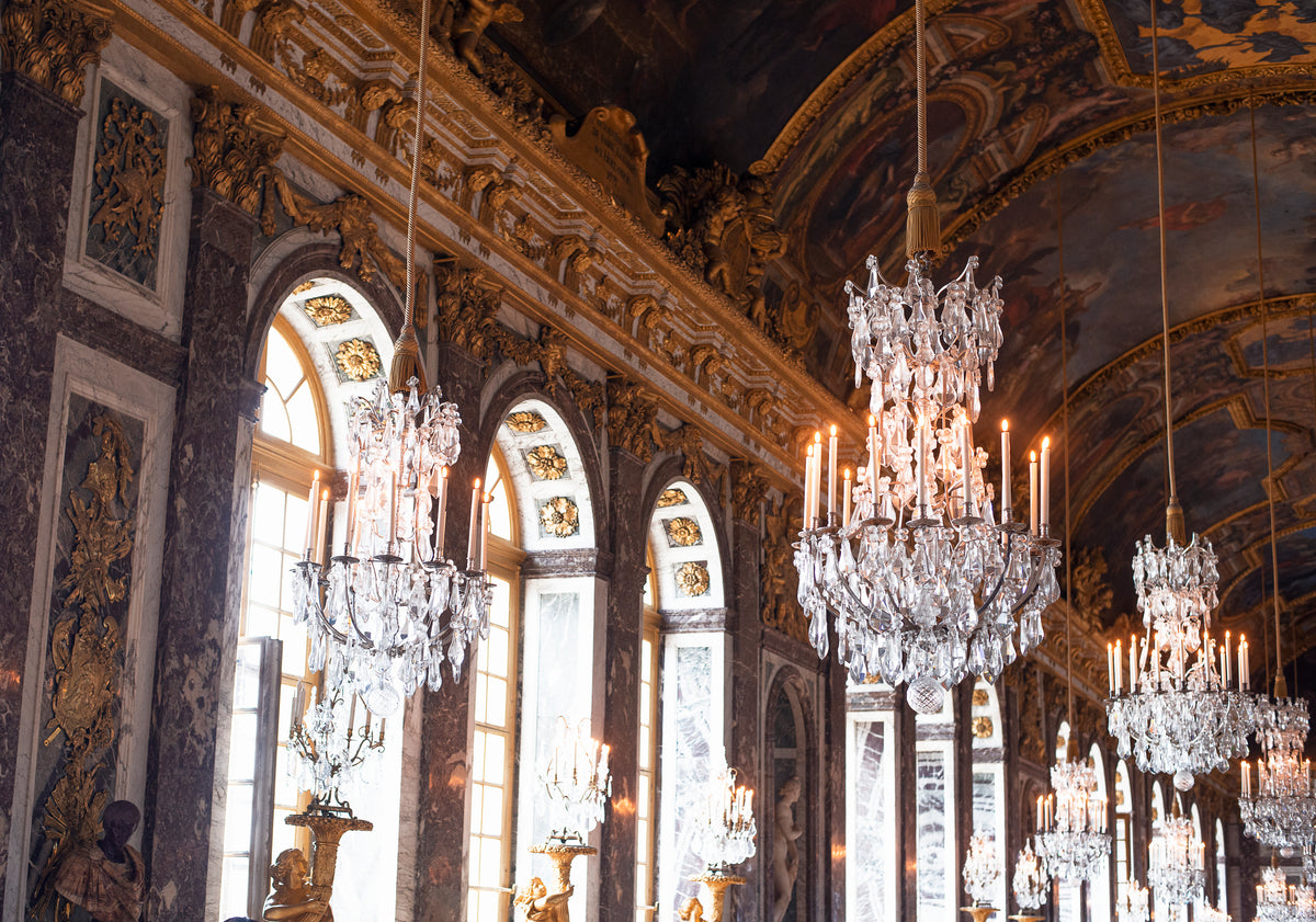 Crystal chandeliers illuminating an ornate historic hall with gilded architectural details.